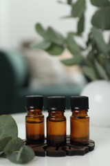 Aromatherapy. Bottles of essential oil and eucalyptus leaves on white table