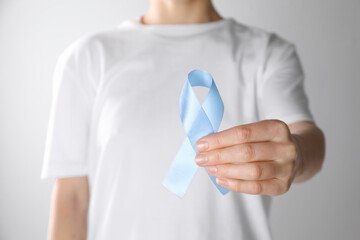 International Psoriasis Day. Woman with light blue ribbon as symbol of support on white background, closeup