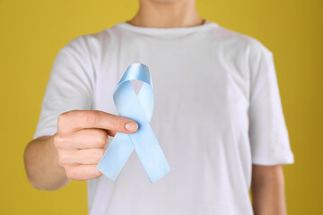 International Psoriasis Day. Woman with light blue ribbon as symbol of support on yellow...
