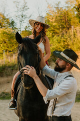 Cowboy is putting reins on a horse while cowgirl is on a horseback at ranch