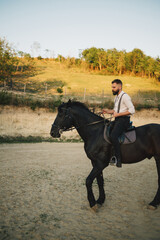 Full length of a cowboy riding a horse in rural area in mountains.