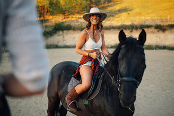 Young attractive horsewoman in western outfit is horseback riding at ranch