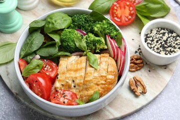 Healthy meal. Delicious chicken, vegetables and spinach served on light grey table, closeup