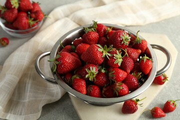Metal colander with fresh strawberries on grey table