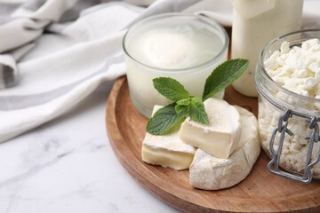 Different dairy products and mint on white marble table