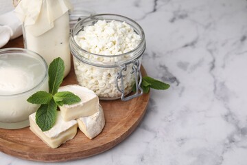 Different dairy products and mint on white marble table, space for text