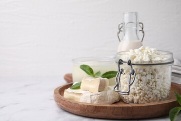 Different dairy products and mint on white marble table, space for text