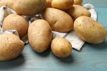 Raw fresh potatoes and napkin on light blue wooden table