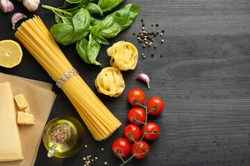 Different types of pasta, products and peppercorns on dark wooden table, flat lay. Space for text