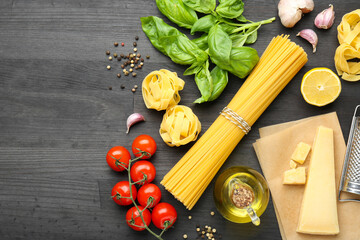 Different types of pasta, products and peppercorns on dark wooden table, flat lay. Space for text