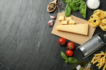 Different types of pasta, spices, garter and products on dark textured table, flat lay. Space for...