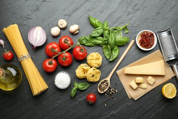 Different types of pasta, spices, garter and products on dark textured table, flat lay