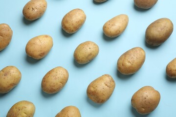 Many fresh potatoes on light blue background, flat lay