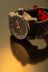 Wristwatch positioned on dark reflective surface, selective focus