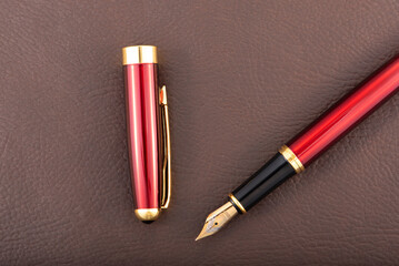 Red fountain pen on leather surface, selective focus