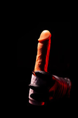 Automatic telescopic silicone dildo for masturbation in a female hand in black gloves on a black background. Products for sex shop, adult gifts for couples