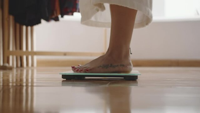 Cropped shot of feet of unrecognizable woman weighing herself on floor in bathroom