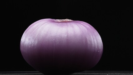Macrography of peeled red onion against a sleek black background takes center stage. Each close-up...