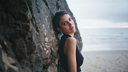 Attractive girl leaning beach cliffs closeup. Sexy model posing sandy seashore
