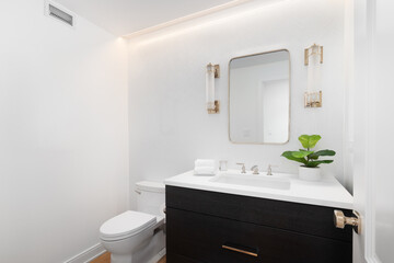 A beautiful bathroom with a dark wood vanity, marble countertop, white herringbone wallpaper, gold light, and rope light built into the ceiling. No brands or labels.
