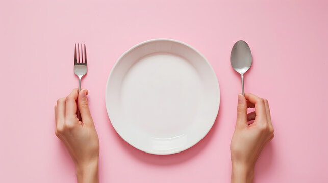 Female hands holding a fork and a spoon next to an empty plate on a pink background closeup top view : Generative AI