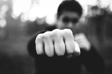 Close-up of a man's brutal fist striking a blow. criminal man striking a blow close-up. black and...