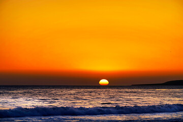 Setting sun over the ocean on the horizon