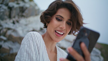 Smiling woman use smartphone outdoors closeup. Joyful brunette messaging online