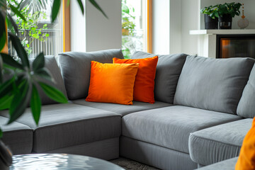 Grey corner sofa with vibrant orange pillows near fireplace. Minimalist interior design of modern living room home.