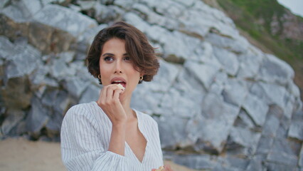 Outdoor woman eating snacks at seashore closeup. Beautiful shy girl resting