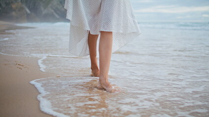 Girl legs going waves beach closeup. Relaxed female traveler walking ocean coast