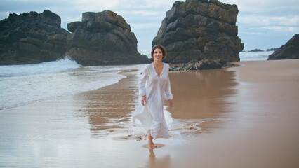 Happy girl strolling ocean shore alone. Smiling woman having fun resting rocky