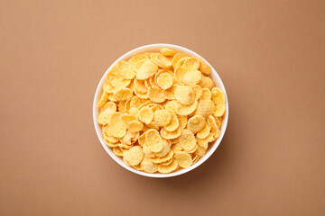 Breakfast cereal. Tasty corn flakes in bowl on brown table, top view