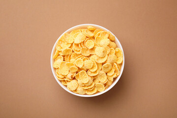 Breakfast cereal. Tasty corn flakes in bowl on brown table, top view