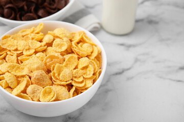 Breakfast cereal. Tasty crispy corn flakes in bowls on white marble table, closeup. Space for text