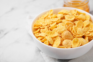 Breakfast cereal. Tasty crispy corn flakes in bowl on white marble table, closeup. Space for text