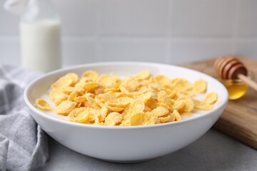 Breakfast cereal. Corn flakes and milk in bowl on light grey table, closeup