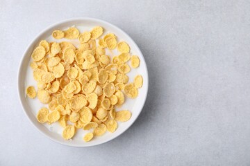 Breakfast cereal. Corn flakes and milk in bowl on light grey table, top view. Space for text