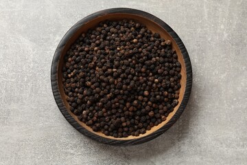 Aromatic spice. Black pepper in bowl on light grey table, top view