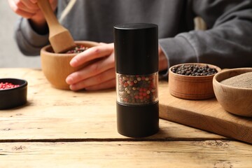 Ground pepper and grains on wooden table, selective focus. Space for text