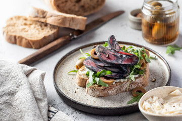 Sandwich with salami sausage, grain bread, cream cheese, olives, aragula and microgreens with...
