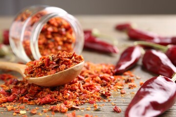 Chili pepper flakes and pods on wooden table, closeup. Space for text