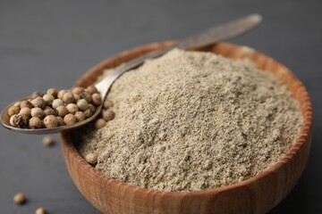 Aromatic spice. Ground pepper in bowl and peppercorns on grey wooden table
