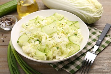 Tasty salad with Chinese cabbage, cucumber and green onion in bowl on wooden table, closeup