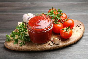 Tasty ketchup, fresh tomatoes, parsley and spices on grey wooden table