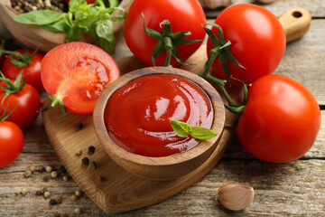 Tasty ketchup, fresh tomatoes, basil and spices on wooden table