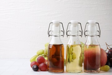 Different types of vinegar and ingredients on light tiled table, closeup. Space for text