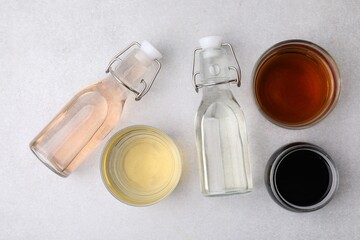 Different types of vinegar on light table, flat lay