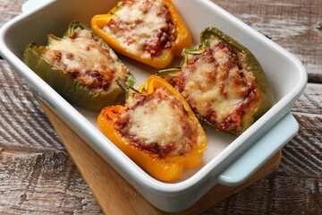 Tasty stuffed peppers in dish on wooden table, closeup
