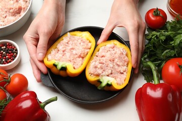 Woman making stuffed peppers with ground meat at white table, closeup